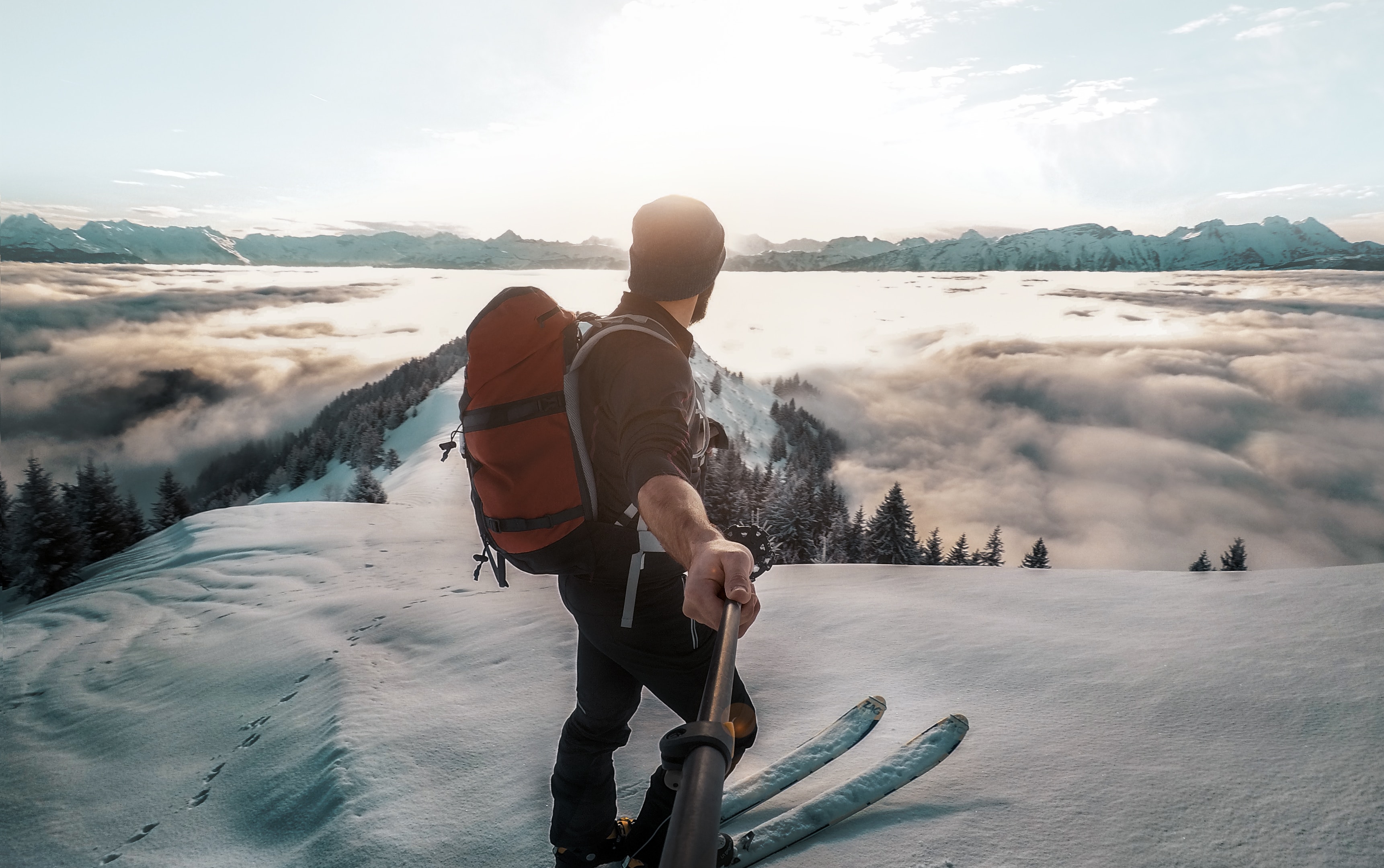 Photo of a man admiring the view from the top of a snowy mountain