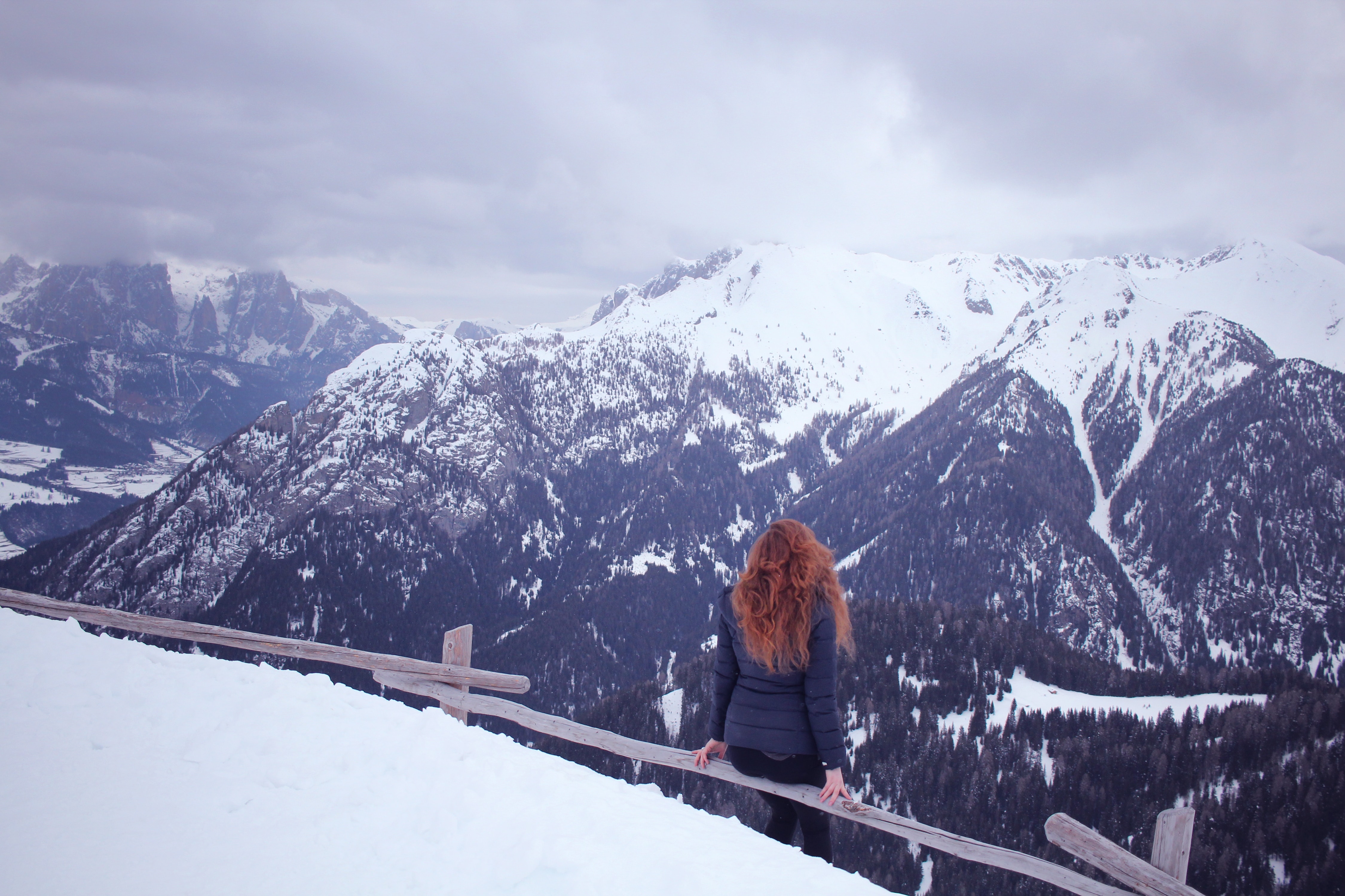 Photo of a woman admiring the view from the top of a snowy mountain